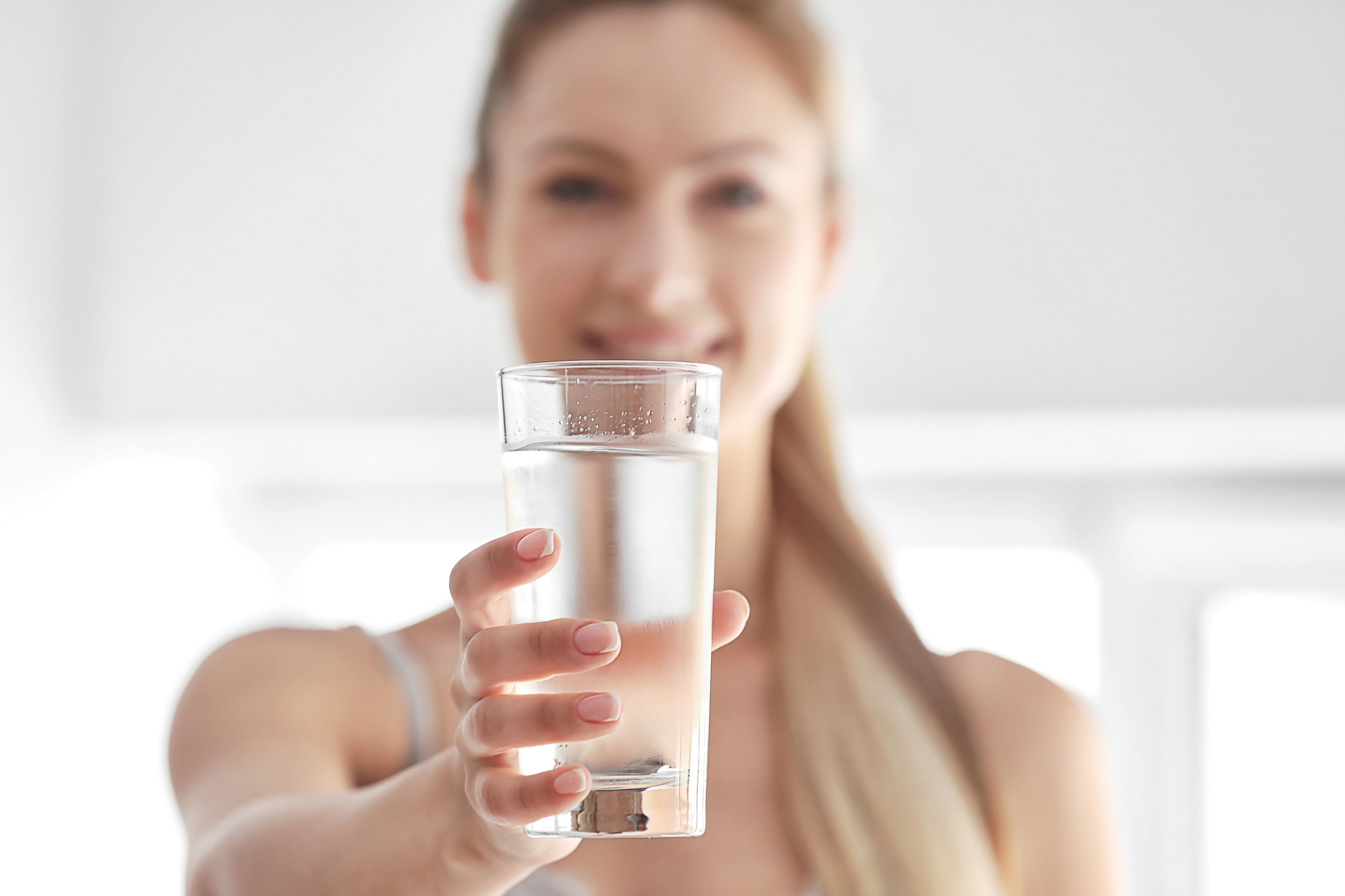 Eine Frau hält ein Glas mit Leitungswasser in die Kamera